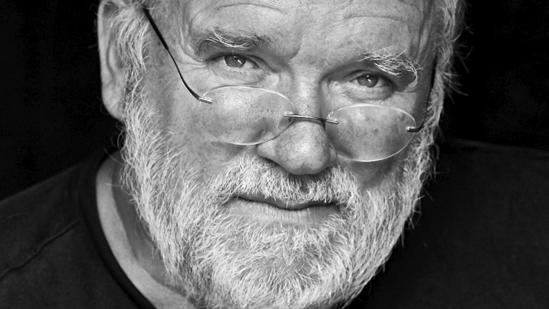 Ritratto in bianco e nero di Peter Lindbergh, fotografo iconico della moda, noto per i suoi scatti autentici e naturali di supermodelle.