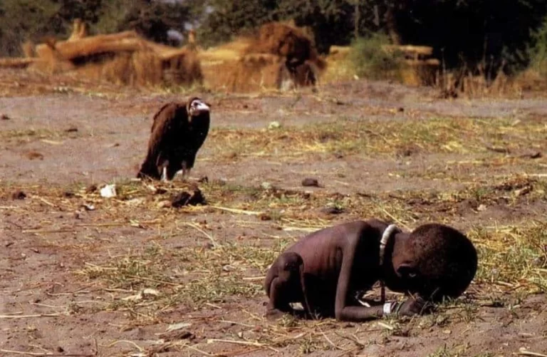 Bambina sudanese accasciata a terra per la fame mentre un avvoltoio osserva a distanza, scatto del 1993 di Kevin Carter in Sudan.