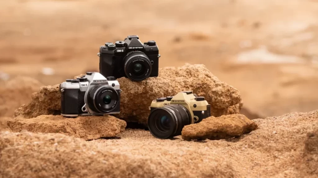 la nuova fotocamera olympus om5 sulla sabbia in diverse colorazioni